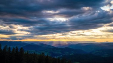 Cloudy weather over low hills covered with spruce evergreen forests in Rhodope Mountains against backdrop of sunset sky, and mystical thick white fog between mountain ranges. UHD 8K video timelaps