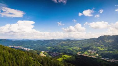View from high rock to old village Smolyan with green meadows for cattle walking and houses, between mountain range of Rhodope Mountains sheltered by spruce forests. UHD 4K video footage timelaps