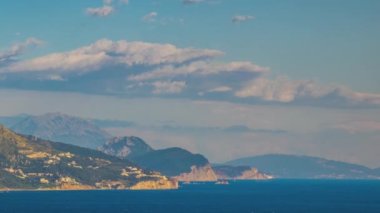 The steep slopes of the Montenegrin Mountains with resort hotels, tourist historical sites and summer green vegetation are washed by calm blue dark waters of the Adriatic Sea. UHD 4K video timelaps