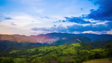 Multicolored evening sky with small clouds and sunny sunset light over the mountain valley of the Rhodope Mountains with a small lonely intermountain village. UHD 4K video timelaps