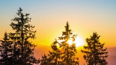 A mountain valley with mountain peaks of the Rhodope Mountains covered with dense spruce dark forests is shaded under a cloudy evening sunset bright sunny sky. UHD 4K video timelaps