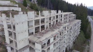 Rodop Dağları 'nın dağ ormanlarındaki vahşi vadisinde otoyol boyunca uzanan çok katlı ve bitmemiş büyük bir bina. UHD 4K video gerçek zamanlı