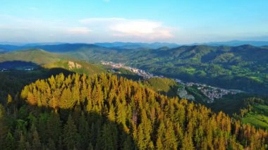 View from high rock to old village town Smolyan with green meadows for cattle walking and houses, between mountain range of Rhodope Mountains sheltered by spruce forests. UHD 4K video realtime