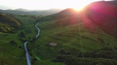 Dönen asfalt bir dağ yolu yüksek yeşil tepeleri geçer ladin ormanları ile kaplı ve taze bahar geniş çayırları bulutlu gri sınırsız gökyüzüne karşı. UHD 4K video gerçek zamanlı