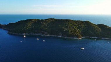 Tarihsel antik turizm adası Aziz Niklas 'ta, açık arkaplan üzerindeki gök mavisi Adriyatik Denizi' nin kayalık kıyılarında bitki örtüsü ile. UHD Video gerçek zamanlı 4K