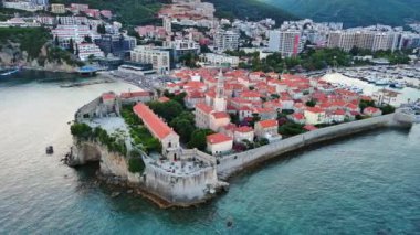 Küçük gemileri ve tekneleri olan deniz turizm limanı antik tarihi Budva adası yakınlarındaki Adriyatik Denizi 'nde romantik bulutlu gökyüzüne karşı. UHD Video gerçek zamanlı 4K