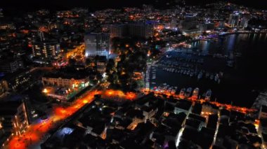 Karadağ dağlarının yamaçlarına ve Adriyatik Denizi yakınlarındaki yıldızlı karanlık gökyüzüne karşı renkli elektrik ışıkları ve plajları olan bir turizm şehri. UHD Video gerçek zamanlı 4K