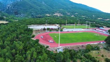 Yunanistan 'ın Litochoro kenti yakınlarındaki spor sahası ve futbol sahası, yüksek seviyeli Olimpos Dağı ve bulutlu gökyüzünün arka planına karşı yeşil bitki örtüsüyle kaplı. UHD Video gerçek zamanlı 4K
