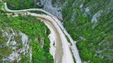 Dar, dolambaçlı bir dağ yolu, Rodop Dağları 'ndaki mavi bulutlu bir gökyüzünün altında yeşil yay dağ bitkilerinin bulunduğu dağ kanyonlarından geçer. UHD 4K video gerçek zamanlı