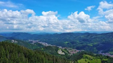 View from high rock to old village town Smolyan with green meadows for cattle walking and houses, between mountain range of Rhodope Mountains sheltered by spruce forests. UHD 4K video realtime