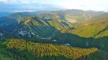 View from high rock to old village town Smolyan with green meadows for cattle walking and houses, between mountain range of Rhodope Mountains sheltered by spruce forests. UHD 4K video realtime