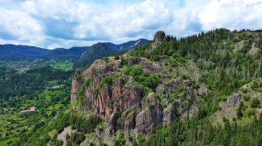 View from high rock to old village town Smolyan with green meadows for cattle walking and houses, between mountain range of Rhodope Mountains sheltered by spruce forests. UHD 4K video realtime