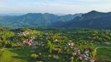 Green spring mountain valley sheltered by mountain vegetation and spruce dark forests with small old village of Smolyan, with grassy meadows where hungry motley sheep graze. UHD 4K video realtime