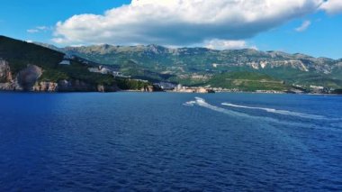 Birkaç küçük turist motorlu botu mavi deniz yüzeyinde yüzerek sonsuz ufuk ve mavi açık gökyüzünün arka planında beyaz köpüklü pürüzsüz bir desen oluşturur. UHD Video gerçek zamanlı 4K