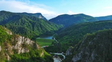Dar, dolambaçlı bir dağ yolu, Rodop Dağları 'ndaki mavi bulutlu bir gökyüzünün altında yeşil yay dağ bitkilerinin bulunduğu dağ kanyonlarından geçer. UHD 4K video gerçek zamanlı