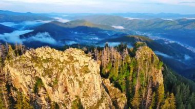 High rocky wild mountain range of Rhodope Mountains covered with green vegetation, against backdrop of mountain valley covered with dense dark spruce forests and blue cloudy sky. UHD 4K video realtime