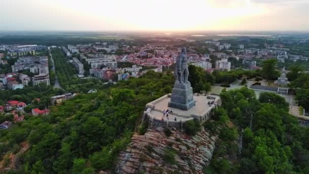 ソ連時代の戦士アロヤの大規模な具体的な歴史的な像暖かい光線で明るい夕日を背景に美しいブルガリアの山間の町プロヴディフ Uhd 4Kビデオリアルタイム — ストック動画