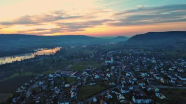 Yeşil tarlalar ve çayırlar, ormanlık tepeler ve dağlar, küçük köyler ve çiftlikler ve geniş yansıtıcı nehir Rhine üzerinde sihirli bulutlu bir akşam gökyüzü. 4K UHD video gerçek zamanlı