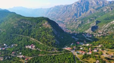 Deniz ünlü Kotor Koyu tatil köyü plajları ve otelleri, açık mavi güneşli gökyüzünün zeminine karşı Karadağ dağlarının gölgesindeki gök mavisi Adriyatik Denizi. UHD Video gerçek zamanlı 4K