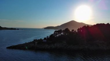 Mavi bulutlu gökyüzünde parlayan yaz güneşi Karadağ dağlarının siluetlerini ve ünlü Kotor Körfezi kıyılarını aydınlatıyor. UHD Video gerçek zamanlı 4K