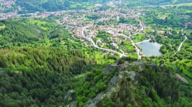 Yüksek kayadan eski köy kasabası Smolyan 'a sığır yürüyüşü için yeşil çayırlar ve dağ sırasındaki Rodop Dağları arasında ladin ormanlarıyla korunan evler. UHD 4K video gerçek zamanlı