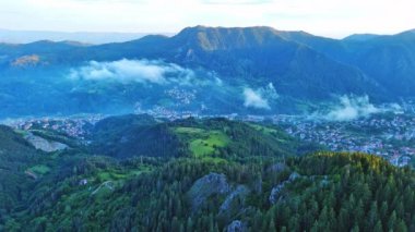 High rocky wild mountain range of Rhodope Mountains covered with green vegetation, against backdrop of mountain valley covered with dense dark spruce forests and blue cloudy sky. UHD 4K video realtime