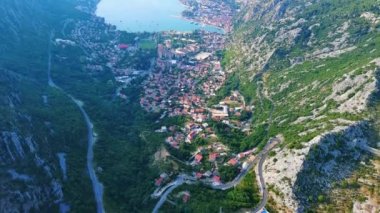 Deniz ünlü Kotor Koyu tatil köyü plajları ve otelleri, açık mavi güneşli gökyüzünün zeminine karşı Karadağ dağlarının gölgesindeki gök mavisi Adriyatik Denizi. UHD Video gerçek zamanlı 4K