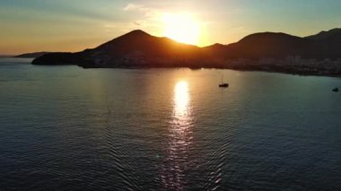 Budva ve Becici tatil beldeleri, sakin Adriyatik Denizi yakınlarında lüks oteller ve rahat plajlarla Karadağ Dağları ve mavi gökyüzüne karşı. UHD Video gerçek zamanlı 4K