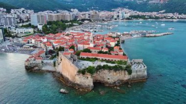Küçük gemileri ve tekneleri olan deniz turizm limanı antik tarihi Budva adası yakınlarındaki Adriyatik Denizi 'nde romantik bulutlu gökyüzüne karşı. UHD Video gerçek zamanlı 4K