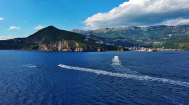 Birkaç küçük turist motorlu botu mavi deniz yüzeyinde yüzerek sonsuz ufuk ve mavi açık gökyüzünün arka planında beyaz köpüklü pürüzsüz bir desen oluşturur. UHD Video gerçek zamanlı 4K