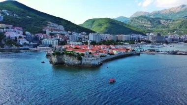 Küçük gemileri ve tekneleri olan deniz turizm limanı antik tarihi Budva adası yakınlarındaki Adriyatik Denizi 'nde romantik bulutlu gökyüzüne karşı. UHD Video gerçek zamanlı 4K