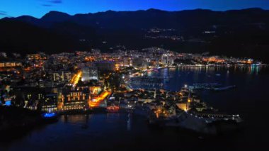 Karadağ dağlarının yamaçlarına ve Adriyatik Denizi yakınlarındaki yıldızlı karanlık gökyüzüne karşı renkli elektrik ışıkları ve plajları olan bir turizm şehri. UHD Video gerçek zamanlı 4K