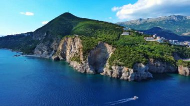 Sığ gök mavisi Adriyatik Denizi 'nin dalgaları üzerinde vahşi yeşil bitki örtüsüyle kayalık bir uçurum. UHD Video gerçek zamanlı 4K