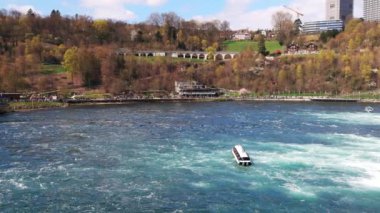 Turistler için büyük turist tekneleri, İsviçre 'deki eski kasabanın arka planına karşı bir sürü güzel beyaz nemli püskürtüyle ünlü Ren Şelalesi' nin yanında yüzüyor. 4k video yavaş çekim UHD