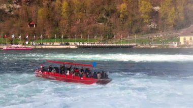 Turistler için büyük turist tekneleri, İsviçre 'deki eski kasabanın arka planına karşı bir sürü güzel beyaz nemli püskürtüyle ünlü Ren Şelalesi' nin yanında yüzüyor. 4k video yavaş çekim UHD