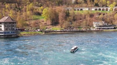 Turistler için büyük turist tekneleri, İsviçre 'deki eski kasabanın arka planına karşı bir sürü güzel beyaz nemli püskürtüyle ünlü Ren Şelalesi' nin yanında yüzüyor. 4k video yavaş çekim UHD