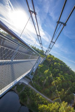 Rappbodetalsperre Gölü üzerindeki yaya asma köprüsü ve Almanya 'nın Harz Dağları Ulusal Parkı' ndaki Rappbode Nehri, güneşli bir günde