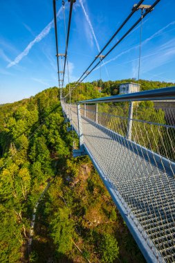 Rappbodetalsperre Gölü üzerindeki yaya asma köprüsü ve Almanya 'nın Harz Dağları Ulusal Parkı' ndaki Rappbode Nehri, güneşli bir günde