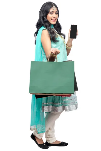 買い物袋を持っているインドの女性と白い背景に隔離された空の携帯電話の画面を示しています コピースペースのための空の携帯電話の画面 — ストック写真
