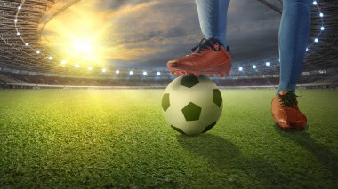 Futbol oyuncusu mavi formalı adam elinde topla futbol sahasında duruyor.
