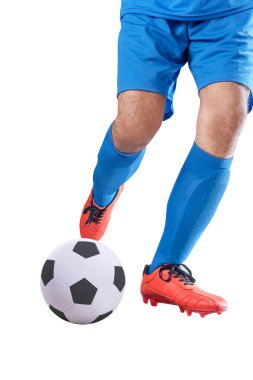 Mavi formalı futbolcu topa vuruyor. Beyaz arka planda yalnız poz veriyor.
