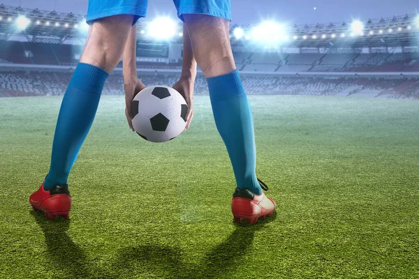 stock image The rear view of a football player man in a blue jersey putting the ball on the football field