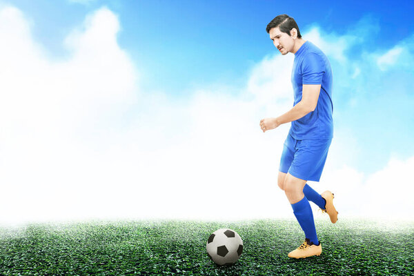 Asian football player man in a blue jersey dribbling the ball on the football field