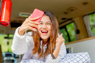 Karavanın içinde cep telefonu kullanan Asyalı kadın kamp faaliyetlerinin keyfini çıkarıyor.