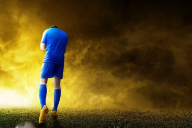 Mavi formalı Asyalı futbolcunun arka görüntüsü futbol sahasındaki zaferini kutluyor.