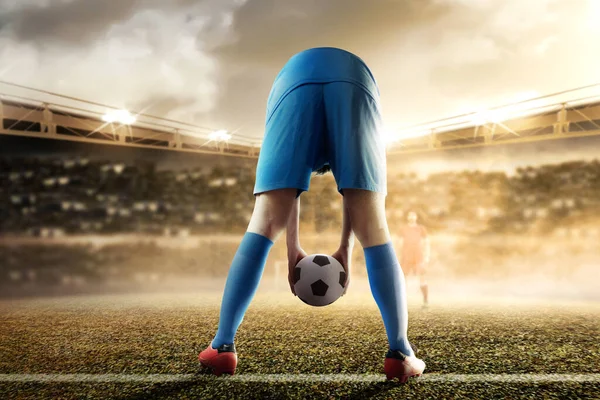 一个身穿蓝色球衣的足球运动员把球放在足球场上的后视镜 — 图库照片