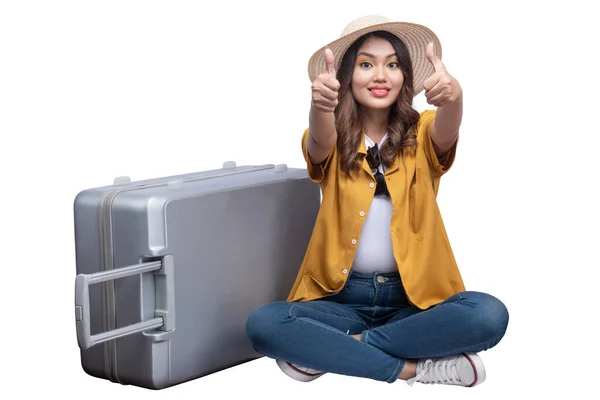 亚洲妇女 头戴一顶帽子 手提箱 坐在那里 用大拇指在白色的背景下显得孤立无援 — 图库照片