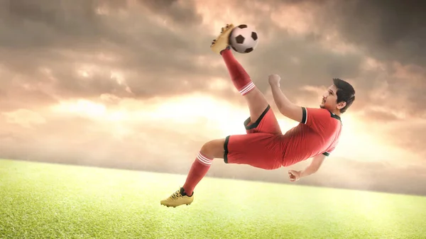 Ασιάτης Ποδοσφαιριστής Κόκκινη Φανέλα Κλωτσάει Την Μπάλα Στο Γήπεδο — Φωτογραφία Αρχείου