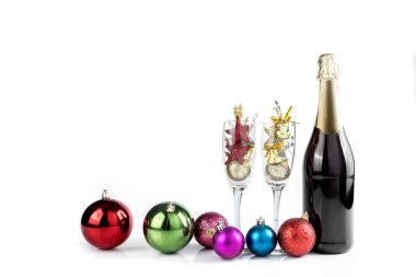 Şampanya şişesi ve beyaz arka planda Noel süslemeleri olan şampanya bardağı.
