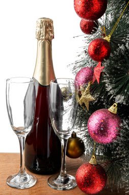 Şampanya şişesi ve beyaz arka planda Noel ağacı olan şampanya bardağı.
